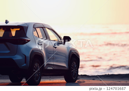 朝日の海をバックにシルバー色の車 124701687