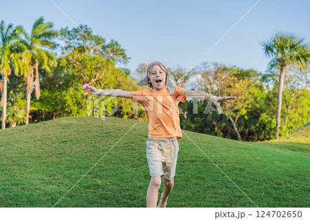 Boy wearing a pilot hat running through the grass with a toy airplane, dreaming of adventures. Childhood, imagination, and freedom concept Boy wearing a pilot hat running through the grass with a toy airplane, dreaming of adventures. Childhood, imagination, and freedom concept 124702650