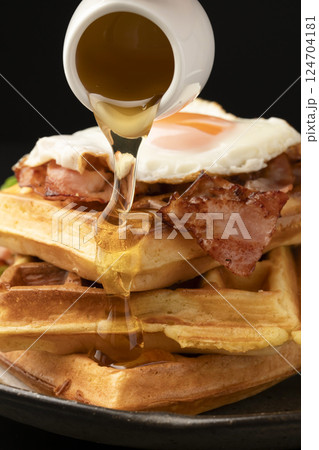 ワッフルとベーコンエッグの朝食 ワッフルにはちみつをかける 124704181