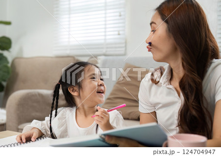 Joyful Learning and Fun Moments. A mother and daughter share laughs during study time at home. 124704947