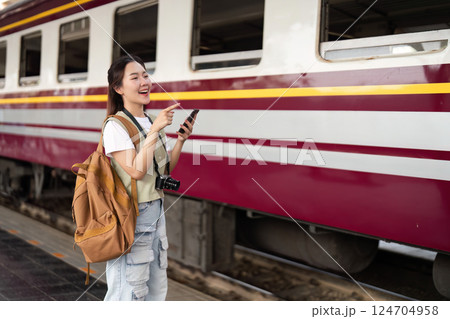 Joy and Anticipation of Travel. A woman with a camera smiling and pointing, excited for her train journey. 124704958