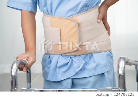 Asian senior pain back wearing elastic support belt with walker. 124705123