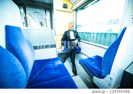 電車の車内で、窓の外を見つめるシニア男性 電車の車内で、窓の外を見つめるシニア男性 124705488