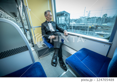 電車の車内で、窓の外を見つめるシニア男性 電車の車内で、窓の外を見つめるシニア男性 124705489