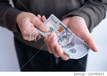 Cropped shot view of someone holding one hundred American dollar banknotes in hands. 124705621