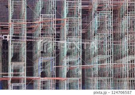 A large number of scaffoldings are used in large construction projects. Scaffolding for on construction site of the new building. 124706587
