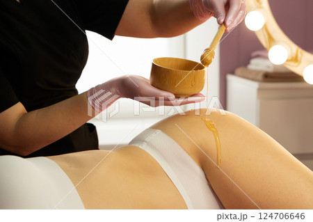 Honey flows smoothly from dipper during wellness skin treatment. 124706646