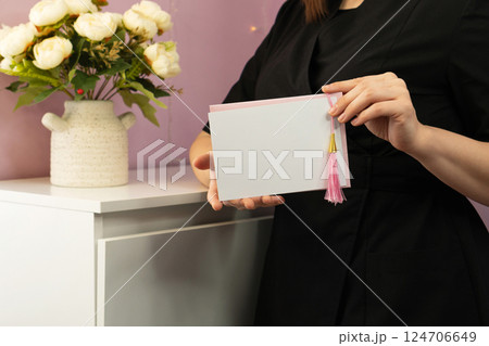 Close-up of woman's hands presenting blank decorative greeting card. Close-up of woman's hands presenting blank decorative greeting card. 124706649
