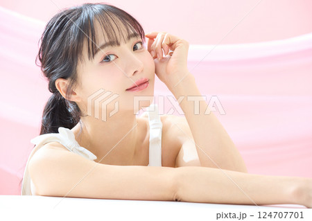 ピンク背景で撮影をした若い女性の爽やかな美容イメージ 124707701