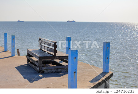 An old wooden bench on jetty, Rest area at the fish pier. An old wooden bench on jetty, Rest area at the fish pier. 124710233