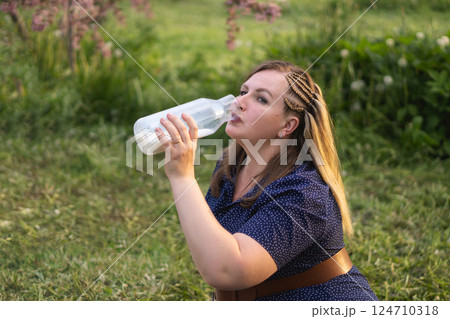 A woman is savoring a refreshing drink of milk while enjoying the beauty of nature outdoors A woman is savoring a refreshing drink of milk while enjoying the beauty of nature outdoors 124710318