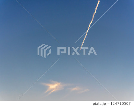 春の夕日の空に飛行機雲03 124710507