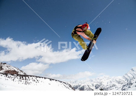 Beginner snowboarder riding on sunny day, performing trick in air. Sport tourist snapshot while snowboarding during winter vacation Beginner snowboarder riding on sunny day, performing trick in air. Sport tourist snapshot while snowboarding during winter vacation 124710721