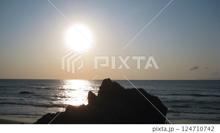 海に沈む夕日と奇岩 124710742
