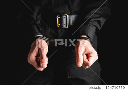 Man in uniform hands in steel handcuffs. Corruption in law enforcement, man caught breaking the law 124710750