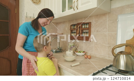 A Mother and Her Child Cooking Together in a Cozy and Inviting Kitchen Environment A Mother and Her Child Cooking Together in a Cozy and Inviting Kitchen Environment 124710814