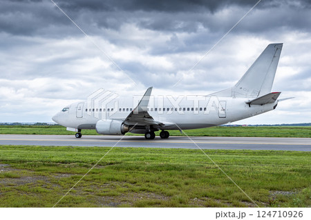 White passenger plane taxiing at the airport in cloudy weather White passenger plane taxiing at the airport in cloudy weather 124710926