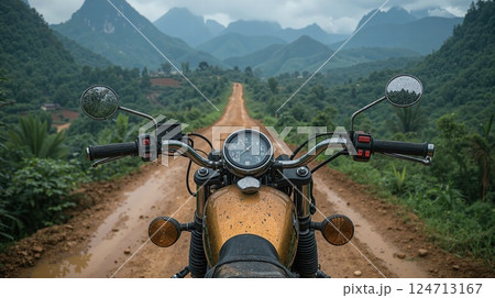 Adventure on dirt path through lush mountains - motorcycle touring journey 124713167