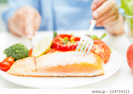 Asian elderly woman patient eating salmon stake and vegetable salad for healthy food in hospital. 124714321
