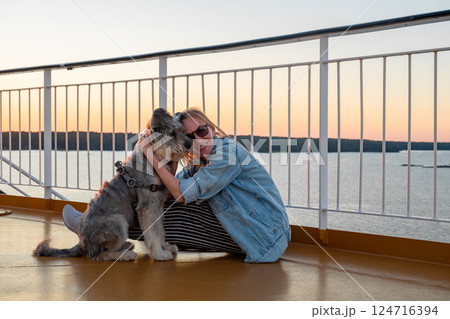 Young woman sitting on a deck of a cruise ship with her dog Young woman sitting on a deck of a cruise ship with her dog 124716394