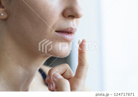 Woman applying cream on dry lips. Closeup, selective focus. Woman applying cream on dry lips. Closeup, selective focus. 124717871