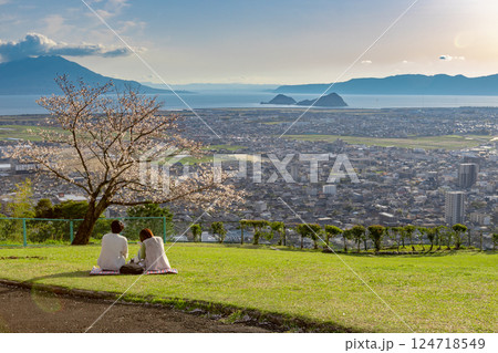 鹿児島県霧島市の城山公園からの風景とピクニックしている若いカップル 鹿児島県霧島市の城山公園からの風景とピクニックしている若いカップル 124718549