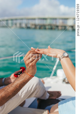 Closeup man putting engagement ring on woman hand on the boat 124719369