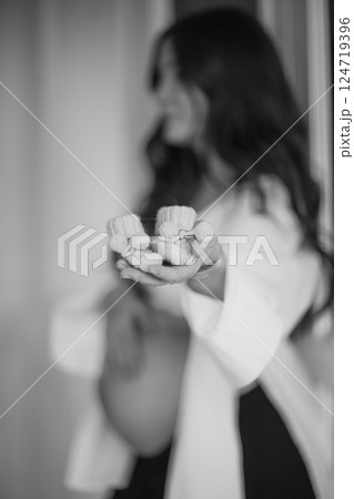 Beautiful pregnant woman at home. Closeup little shoes for baby in hands Beautiful pregnant woman at home. Closeup little shoes for baby in hands 124719396