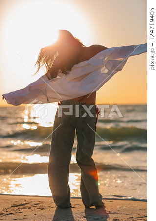 Silhouette of the beautiful girl enjoying beautiful sunset on the beach 124719405