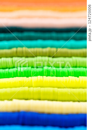 A vibrant collection of clay beads, neatly arranged by color on a white table, ready to inspire young crafters to create their own unique bracelets. 124720006