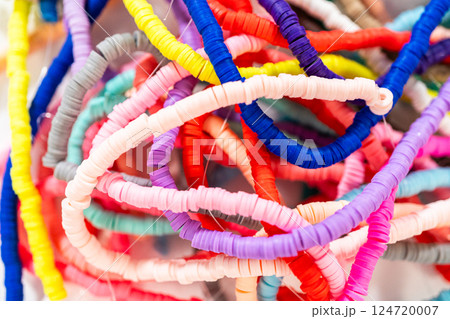 A vibrant collection of clay beads, neatly arranged by color on a white table, ready to inspire young crafters to create their own unique bracelets. 124720007