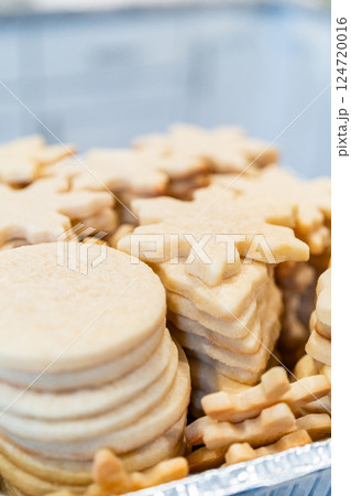 Carefully stacking the beautifully crafted snowflake-shaped sugar cookies into a foil pan, ready for freezing as delightful Christmas treats. Carefully stacking the beautifully crafted snowflake-shaped sugar cookies into a foil pan, ready for freezing as delightful Christmas treats. 124720016
