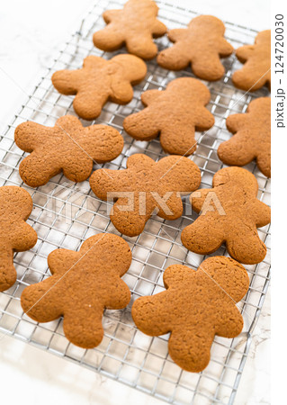 Close-up view of a tray of freshly baked gingerbread man cookies placed on a cooling rack, highlighting festive details. Close-up view of a tray of freshly baked gingerbread man cookies placed on a cooling rack, highlighting festive details. 124720030