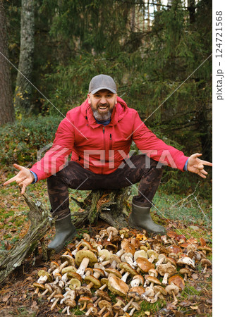 Enthusiastic mushroom forager showcases impressive harvest in forest during fall season 124721568