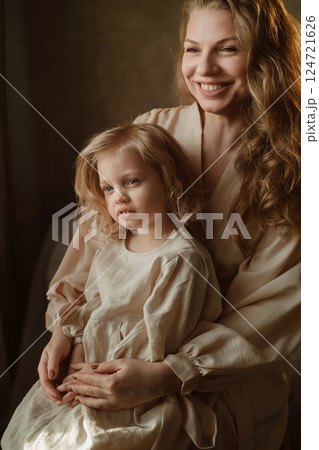 Mother and daughter share a joyful moment in soft natural light within a cozy room during a calm afternoon 124721626