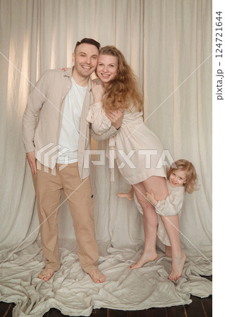 Happy family poses together in a cozy indoor setting, showcasing love and joy during a casual photoshoot 124721644