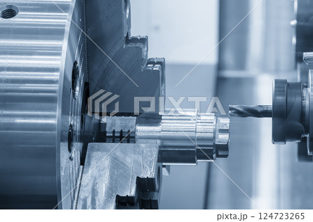 The CNC lathe machine milling cut the metal shaft parts in the light blue scene. 124723265