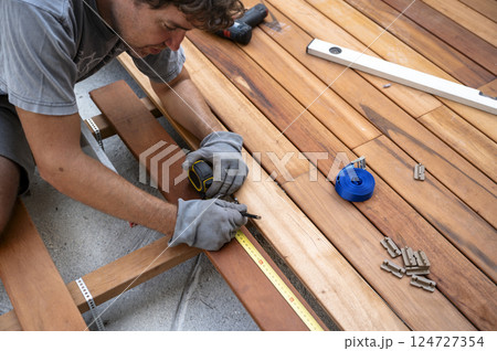 Skilled worker installing wooden deck Skilled worker installing wooden deck 124727354