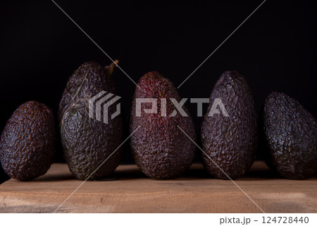 Five Hass avocados on wooden table. 124728440