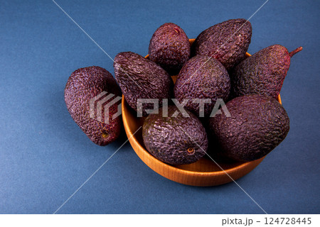Hass avocados in wooden bowl on blue table 124728445