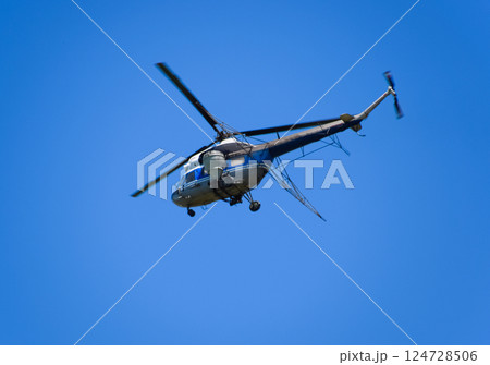A helicopter of agricultural aviation is flying in the blue sky. 124728506