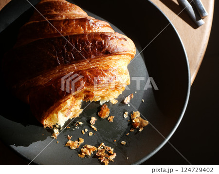 Delicious Croissant on Black Plate with Sunlight Shadows Delicious Croissant on Black Plate with Sunlight Shadows 124729402