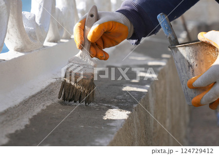 A Construction Worker Carefully Applying the Finishing Touches to a Surface with Brush and Trowel A Construction Worker Carefully Applying the Finishing Touches to a Surface with Brush and Trowel 124729412