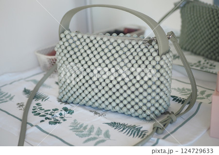 Stylish green beaded handbag on a decorative table 124729633