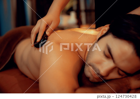 Hot stone massage at spa salon in luxury resort with warm candle light.Quiescent Hot stone massage at spa salon in luxury resort with warm candle light.Quiescent 124730428