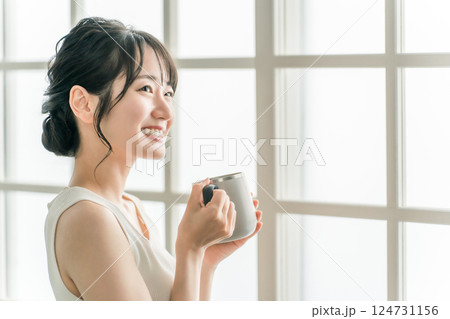 保温マグカップで朝、家でお茶・白湯を飲むリラックスするアジア人女性（温活） 124731156