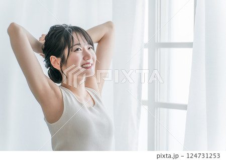 寝起き・起床時にカーテンの前で朝日を浴びる女性(笑顔) 寝起き・起床時にカーテンの前で朝日を浴びる女性(笑顔) 124731253