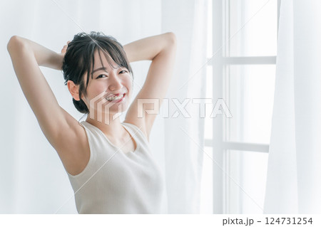 寝起き・起床時にカーテンの前で朝日を浴びる女性(笑顔) 寝起き・起床時にカーテンの前で朝日を浴びる女性(笑顔) 124731254