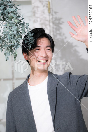 ジャケットを着て木陰で見上げる男性 待ち合わせなどで見上げる手を振る ジャケットを着て木陰で見上げる男性 待ち合わせなどで見上げる手を振る 124732163