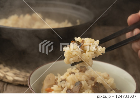 茶碗によそった土鍋で炊いたハマグリの炊き込みご飯を箸で持ち上げる 茶碗によそった土鍋で炊いたハマグリの炊き込みご飯を箸で持ち上げる 124733037